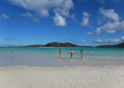 3 girls running into the water of a beach in the whitsunday islands