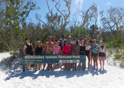 group of tourist standing behind a whitsundays islands national park sign