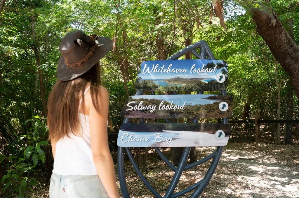 Lady standing by the walking track sign at Whitehaven Beach