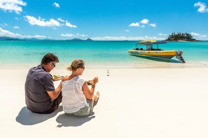 2 people sitting on the sands at Hill Inlet Whitehaven Beach.